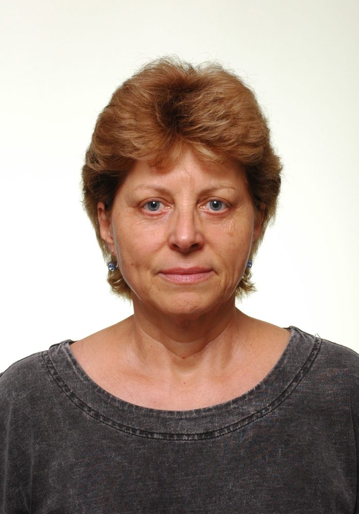 Woman with short brown hair and blue eyes wearing a dark gray top, facing the camera.